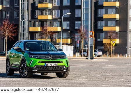 Riga, Latvia - 26 March, 2021: Green Electric Vehicle Opel Mokka-e In The Parking Lot On The Backgro