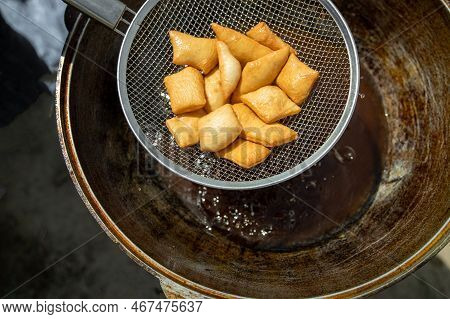 Traditional Kazakh And Central Asian Fresh Baursaks Are Taken Out Of A Large Cauldron. Traditional A