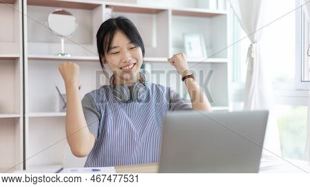 Joyful, Surprised or shocked Asian woman raised her arms all the way because she did a good job the 
