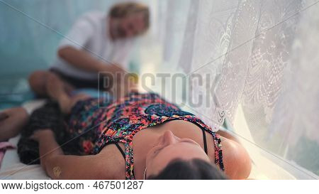 Male Masseur Massages The Legs In A Beautiful White Ornamrental Tent.