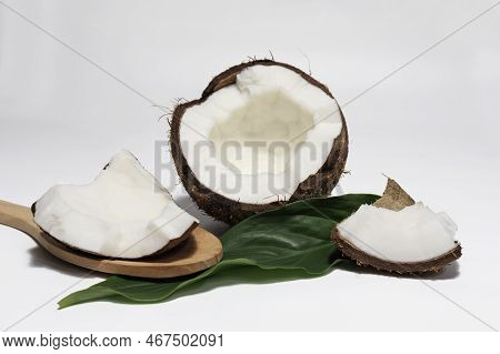 Coconut Broken In Half With Slice Pulp On A Wooden Spoon Among Palm Leaves