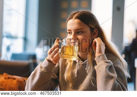 Portrait Of A Joyful Teengirl Enjoying A Cup Of Tea At Cafe. Smiling Beautiful Girl Drinks Hot Tea I
