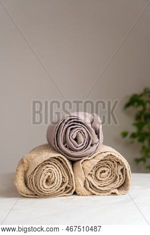 Close-up Of A Composition With Three Twisted Towels On A Massage Table In A Spa Salon Against A Ligh