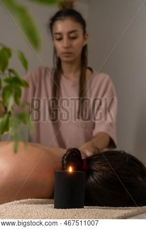 Masseur Massages The Collar Area Of The Woman Lying On The Couch In The Office, Focus On The Candle.