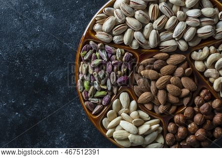 Assortment Of Nuts In Ceramic Bowl On A Black Background, Close Up, Top View, Copy Space. Cashew, Ha