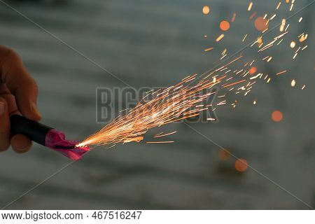 Burning Firecracker With Sparks. Guy Holding A Petard In A Hand. Loud And Dangerous New Years Entert
