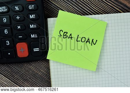 Concept Of Sba Loan Write On Sticky Notes With Calculator Isolated On Wooden Table.