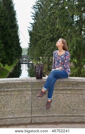 Eautiful Mädchen sitzt auf einer alten Steinbrücke