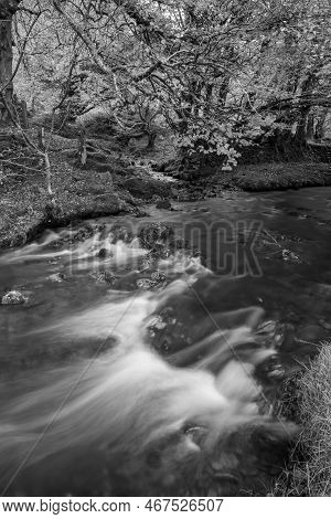 Long Exposure Of The Weir Water River Flowing Downstream Of Robbers Bridge In Exmoor National Park