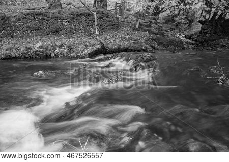 Long Exposure Of The Weir Water River Flowing Downstream Of Robbers Bridge In Exmoor National Park