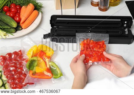 Woman Using Sealer For Vacuum Packing With Plastic Bag Of Red Pepper At White Table, Closeup