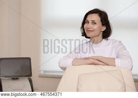 Business Portraits. Confident Female Doctor Posing In Doctor's Smock With Hands Folded In Front Agai