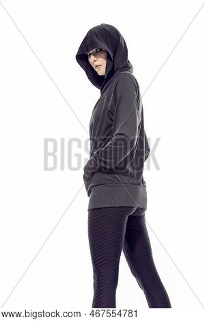 Winsome Sportive Caucasian Female Athlete Posing In Black Hoody While Wearing Fitness Outfit And Loo