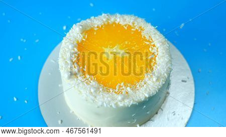 Cake With Orange And Coconut Shavings Spinning On A Blue Background.