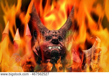 Devil On Fire On A Dark Background. Man In Scary Devil Mask, Halloween. Holding Out His Hand. Hell C