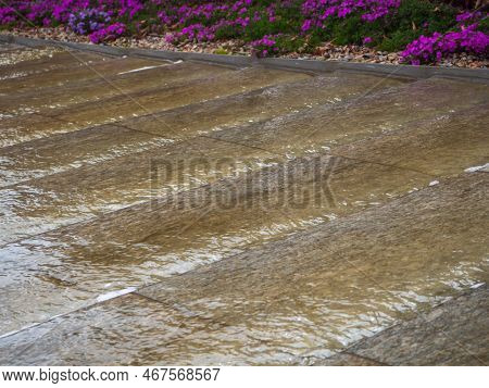 Water Running Down The Steps. Water Flows Down The Decorative Stone Steps Of The Path In The City Pa
