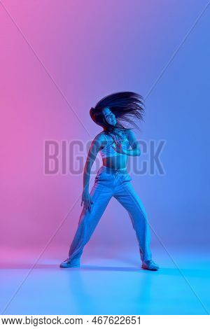 Young Stylish Girl Dancing Hip-hop Over Gradient Pink Blue Background In Neon Light. Sportive Lifest