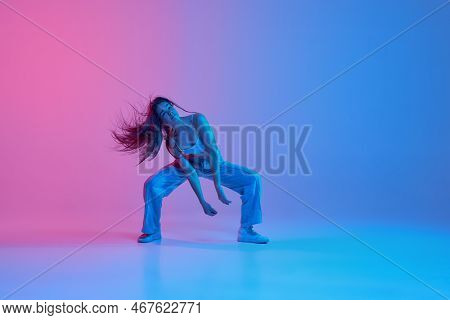 Young Active Girl Dancing Hip-hop Over Gradient Pink Blue Background In Neon Light. Street Style