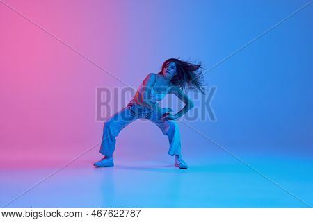 Young Stylish Girl Dancing Hip-hop Over Gradient Pink Blue Background In Neon Light. Dance Show