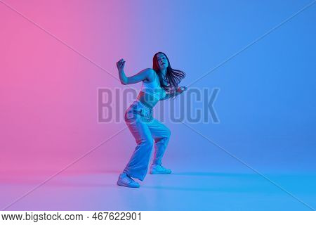 Freestyle. Young Active Girl Dancing Hip-hop Over Gradient Pink Blue Background In Neon Light