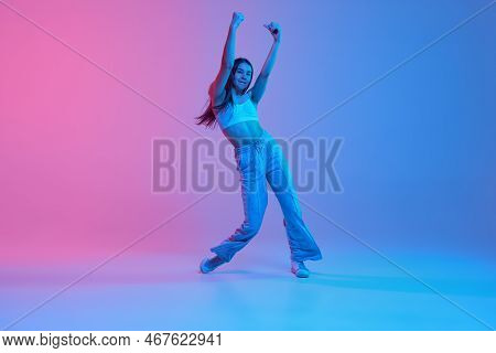 Young Active Girl Dancing Over Gradient Pink Blue Background In Neon Light. Hip Hop Training