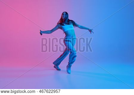 Young Stylish Girl Dancing Over Gradient Pink Blue Background In Neon Light. Dance Expression