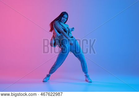 Rhythm. Young Stylish Girl Dancing Hip-hop Over Gradient Pink Blue Background In Neon Light
