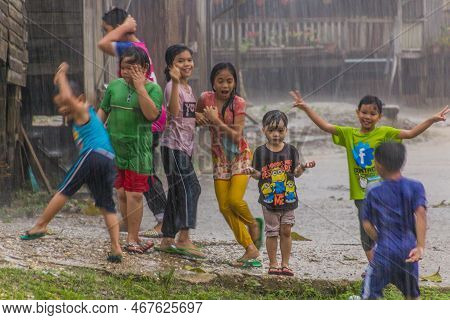 Kinabatangan, Malaysia - February 19, 2018: Children Playing In A Heavy Rain In A Small Village Near