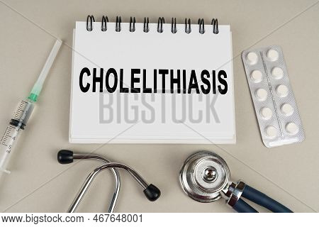 Medical Concept. On A Gray Surface, A Syringe, A Thermometer, A Stethoscope, A Blister And A Notepad