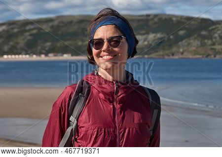 Smiling Woman In An Purpe Tourist Jacket On The Shore Of The Cold Northern Sea