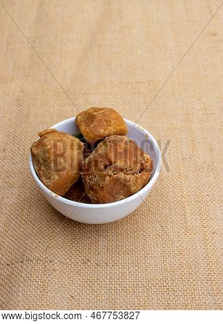 Organic Palm Jaggery Or Indian Gur In A Bowl Isolated On Burlap Fabric In Vertical Orientation