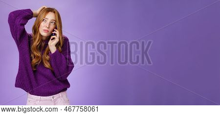 Confused Cute Redhead Female Making Appoinment Via Mobile Phone Scratching Back Of Head And Squintin