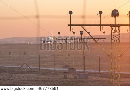 Poland, Krakow, Balice Airport, Runway Lights Andcommercial Aircraft Taxiing At Sunset,