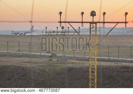 Poland, Krakow, Balice Airport, Runway Lights Andcommercial Aircraft Taxiing At Sunset,