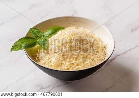 Grated Parmesan In A Bowl Over Marble Background. Bowl Of Shredded Grana Padano Cheese And Green Bas