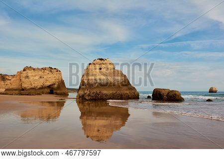 Symmetrical Reflection Of The Limestone Rocks In The Water Of Low Tide. Praia Dos Tres Castelos In P