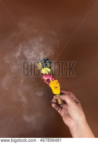 Womens Hands Holding A Smoking Smudge Stick To Banish Bad Energy. Dried Herbs And Flowers Are Tied I