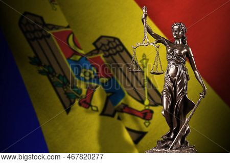 Moldova Flag With Statue Of Lady Justice And Judicial Scales In Dark Room. Concept Of Judgement And 