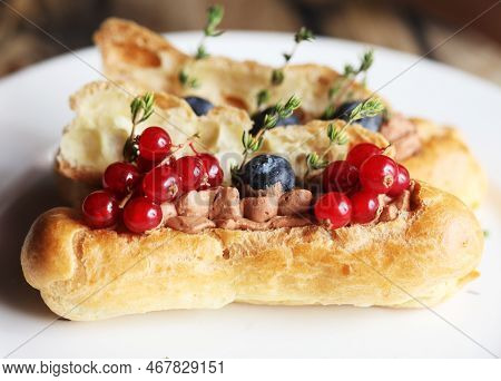 Tasty French Eclairs With Icing, Cream, Fresh Berries And Sugar Decor Elements.