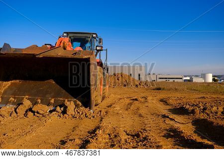 Tractor With Bucket In Sand And Clay.excavator At Construction Site On Houses And Blue Sky Backgroun