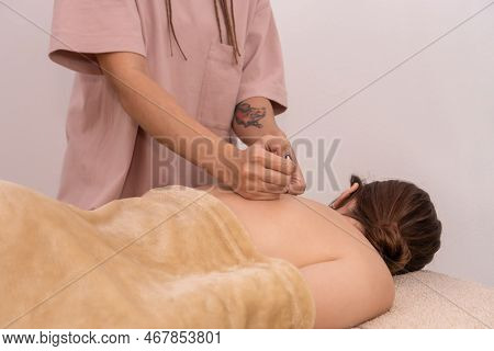 Professional Female Hands Massage The Back And Shoulder Blades Of A Young Brown-haired Woman In A Sp