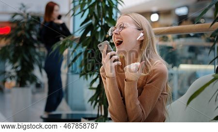 Caucasian Funny Blonde Girl Wears Wireless Headphones Listens To Music In Mobile Musical Application
