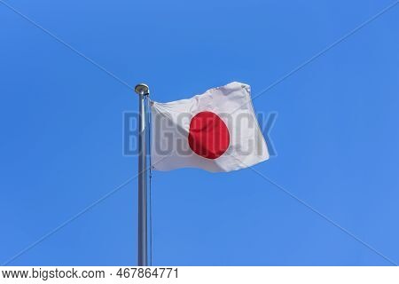 Japanese National Flag Waving In The Wind Against A Sunny Blue Sky.