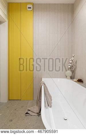Modern Bright Bathroom With Lamella Wall. Big White Bath With Btrown Towel And Orchid.