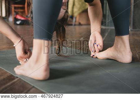 Close-up Side Photo Of A Female New Yoga Teacher Doing A Standing Forward Fold Pose Variation Hookin