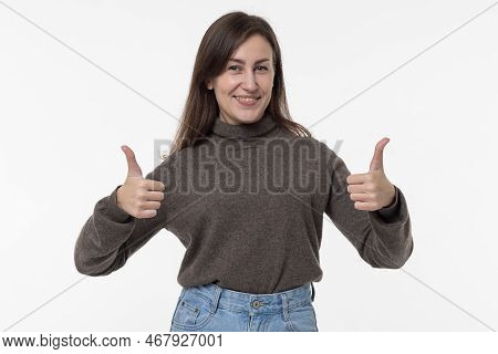 Beautiful Young Smiling Brunette Dressed In Casual Clothes Shows Thumbs Up Isolated On A White Backg