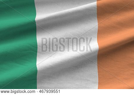 Ireland Flag With Big Folds Waving Close Up Under The Studio Light Indoors. The Official Symbols And