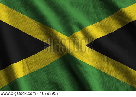 Jamaica Flag With Big Folds Waving Close Up Under The Studio Light Indoors. The Official Symbols And