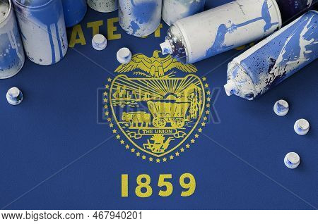 Oregon Us State Flag And Few Used Aerosol Spray Cans For Graffiti Painting. Street Art Culture Conce