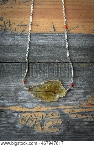 Close Up Pendant With Dry Leaf Inside Concept Photo. Stylish Jewelry. Top View Photography With Rust